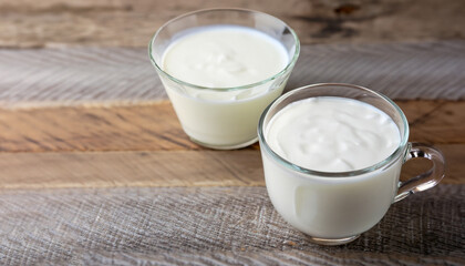 Glass cup of Turkish traditional drink ayran , kefir or buttermilk made from yogurt, homemade yoghurt in glass bowl on rustic table, healthy food