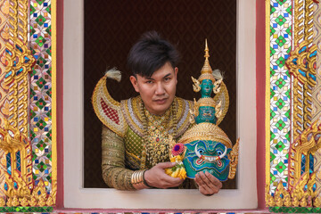 an actor portraying Ravana in a Khon drama, a traditional Thai masked play based on the Ramayana. The actor holds a intricately designed Ravana mask, embodying the character's persona