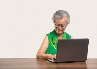 Senior woman typing on laptop keyboard and using live chat app for online communication.