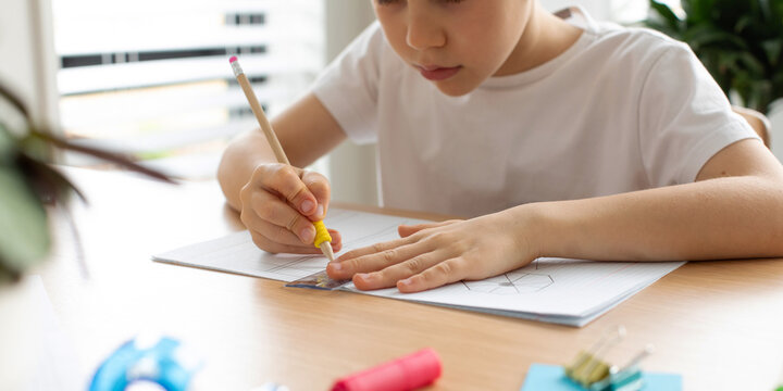 A cute boy makes a drawing with a ruler and pencil. Home lessons. Geometry and drawing.