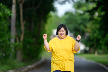 Asian woman with down syndrome smiling happy smiling and looking at camera Fat young woman with down syndrome exercising in the park in the middle of nature