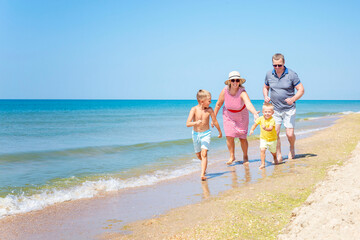 Elderly people play with children on the seashore on a sunny day. Love and tenderness. Active lifestyle and family relationships.