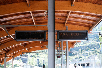 Two tabloids hanging symmetrically, attached to a gray metal post on the platform, on the platform of the train under the wooden planks of the lined roof - obrazy, fototapety, plakaty