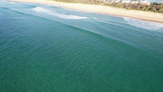 Surfers On Surfboard Floating In The Sea At Kawana Beach In Queensland, Australia. aerial tilt-up