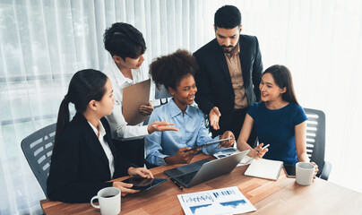 Multiracial analyst team use BI dashboard data to analyze financial report on meeting table. Group of diverse business people utilize data analysis by FIntech for success business marketing. Concord