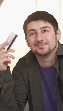 Vertical video. Credit card payment. Banking service. Pensive man thinking of buying purchase daydreaming about financial freedom independence.