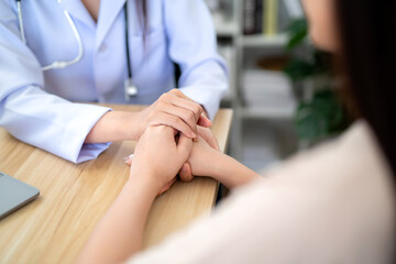 Obraz premium Close up hand of doctor holding female patient's hand to encourage medical treatment and health care in the hospital office.