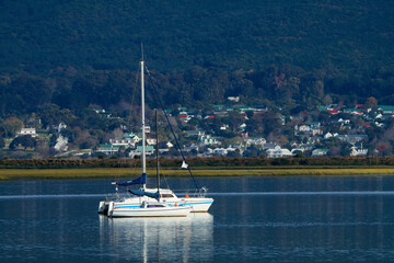 A yacht on a tranquil lagoon with reflection, Knysna, South Africa.