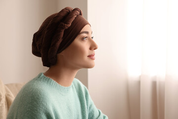 Cancer patient. Young woman with headscarf near window indoors, space for text - obrazy, fototapety, plakaty