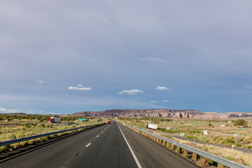 Fototapeta na wymiar Beautiful highway in New Mexico, USA. Picturesque landscape with a road among mountains and dark blue sky on a sunny summer day. New Mexico, USA - 06-17-2023