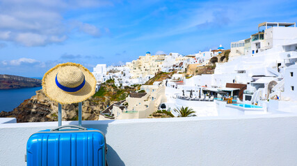 Summer concept with Blue luggage with hat and landscape view of Oia town in Santorini island in Greece , Greek landscape as blue sky background