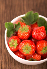 bowl with fresh strawberries on rustic table on wooden background