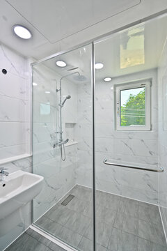 The shower area is separated by a glass partition in the bathroom decorated with Bianco tiles