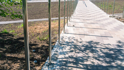 Stainless steel railing. Shiny metal railings along the marble flagstone walkway. Repair of urban infrastructure. Improvement of streets in the city.