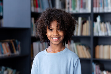 African american schoolboy wearing blue long sleeve t shirt with copyspace over library