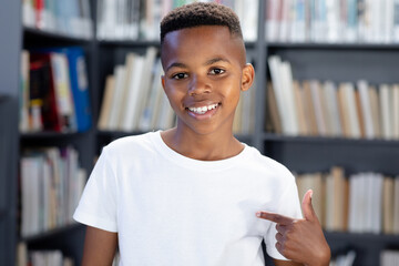 African american schoolboy wearing white t shirt with copyspace over library