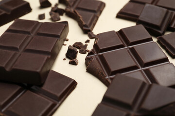 Pieces of delicious chocolate bars on beige background, closeup