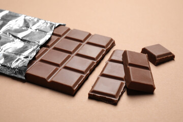 Fototapeta na wymiar Pieces of delicious chocolate bar on beige background
