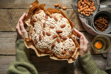 Woman with delicious Italian Easter dove cake (traditional Colomba di Pasqua) at wooden table, top...