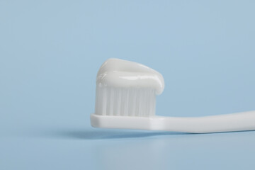 Fototapeta na wymiar Plastic toothbrush with paste on light blue background, closeup