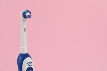 Electric toothbrush on pink background, space for text