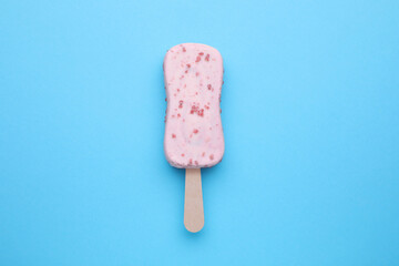Delicious glazed ice cream bar on light blue background, top view