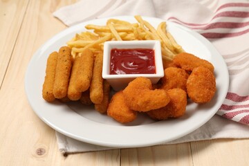 Plate with tasty ketchup, French fries, chicken nuggets and cheese sticks on wooden table, closeup