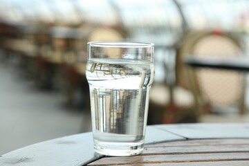 Glass of fresh water on table outdoors, closeup