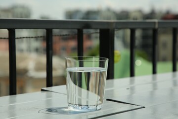 Glass of fresh water on white wooden table outdoors