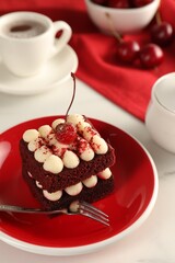 Piece of delicious red velvet cake and fork on white table, closeup