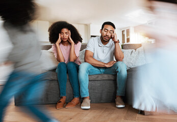 Kids running with stressed parents on the sofa to relax in the living room of their house. Upset, burnout and excited children playing with blur motion on couch with tired exhausted mother and father