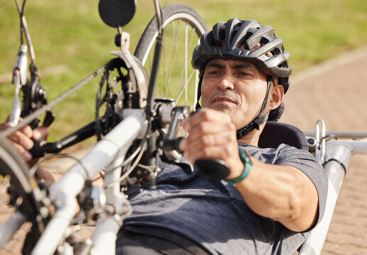 Man with disability, handbike and cycling outdoor for sports, race and endurance contest. Bicycle, male rider and athlete with physical health condition on bike with focus, competition and challenge