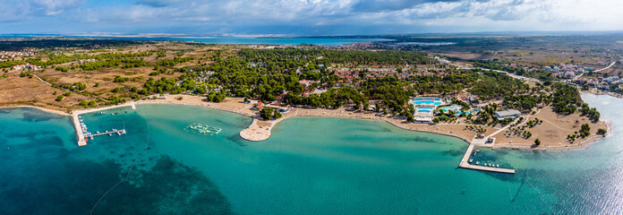 Zaton, Croatia - Aerial panoramic view of Zaton tourist waterfront with turquoise sea water, Nin village and Velebit mountains at background on a sunny summer day in Dalmatia region of Croatia