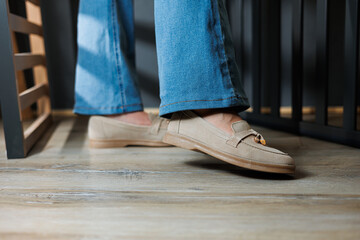 Close-up of female legs in jeans and beige loafers made of genuine leather.