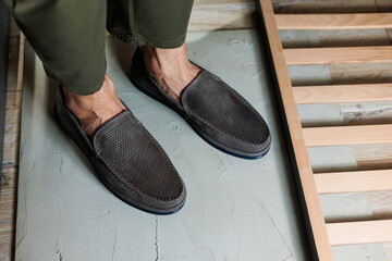 Male legs close-up in jeans and beige genuine leather moccasins.