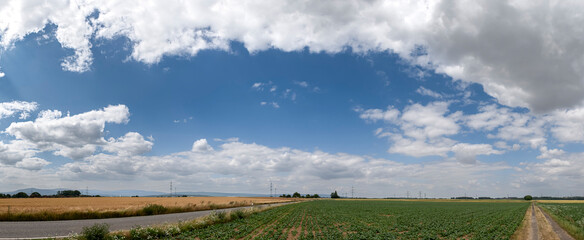 Aufgelockerte Bewölkung über einer landwirtschaftlich genutzten Landschaft mit einer leeren...