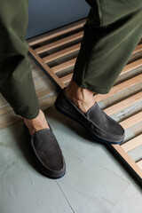 Male legs close-up in jeans and beige genuine leather moccasins.