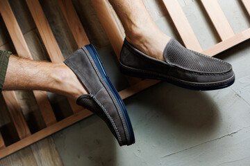 Male legs close-up in jeans and beige genuine leather moccasins.