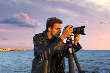 
Beautiful photographer in leather and jeans makes photo video on camera for film, elegantly...