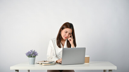 Asian businesswoman or female office worker is working on her tasks on her laptop at her desk.