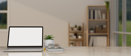 A laptop mockup on a tabletop in a minimal cozy living room. workspace close-up image.