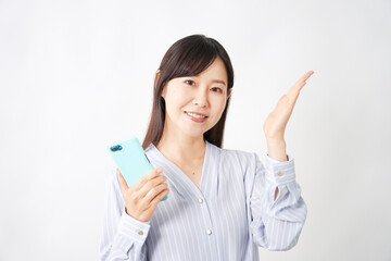 スマートフォンを持って右側を案内するミドルエイジ女性　白背景