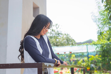 An pretty young lady with long black hair wearing a cardigan and a navy blue long sleeves top, arm...