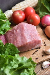 Fresh raw pork on a cutting board with vegetables