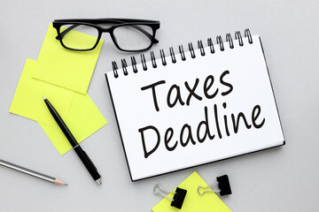 Taxes deadline text on the gray photo on the page. yellow sticker glasses and a black pen on a gray...