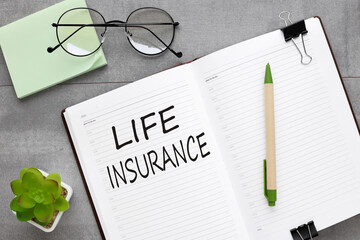 Life Insurance text on white page on open notebook on gray background