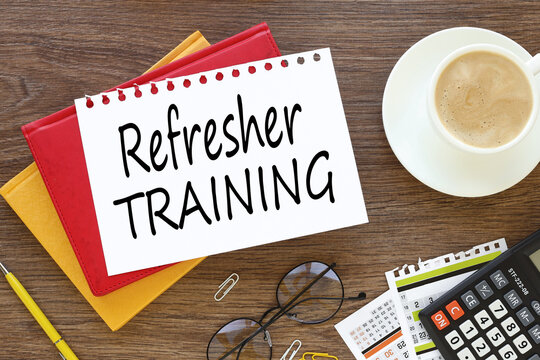 Refresher Training business concept. On a dark work table, three notepads near a calculator plant and a cup of coffee with tex