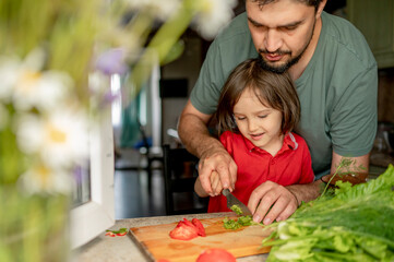 Father teaching son to cut vegetables at home
