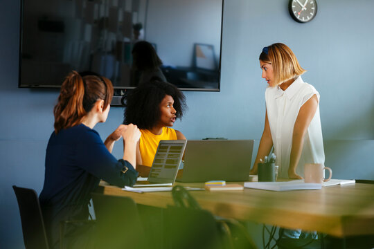 Businesswoman discussing strategy with colleagues in meeting at creative office
