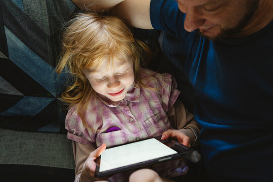 Daughter studying through tablet PC sitting with father